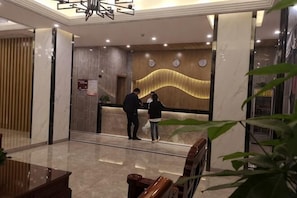 A reception area with a marble reception desk, a clock, and a modern wall design. - Jinqiao Hotel (Shenzhen Longhua) (Shenzhen)