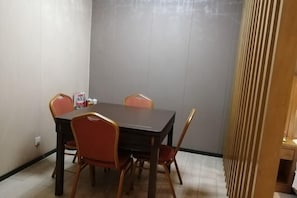A dining area with a rectangular table, four chairs, and a small table with condiments. - Jinqiao Hotel (Shenzhen Longhua) (Shenzhen)