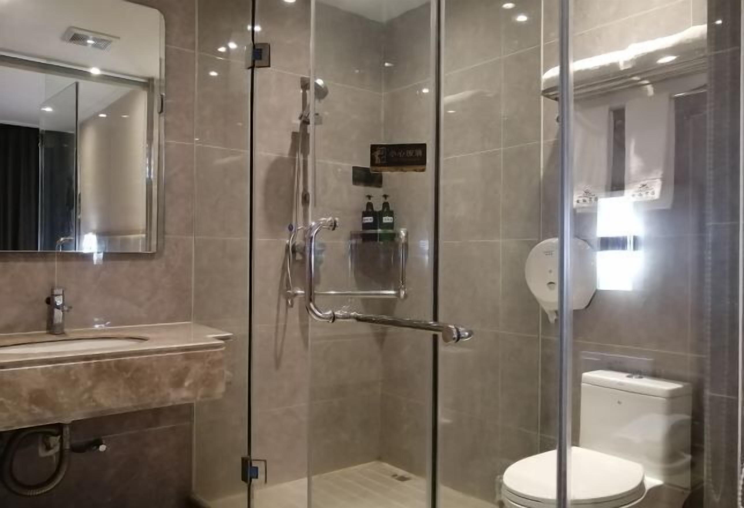 A modern bathroom with a glass-enclosed shower, a sink with a mirror, and a toilet.