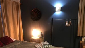 A bedroom with a bed, a bedside table with a lamp, a wall-mounted light, and a coat rack. - Lovely and Comfortable 1-bed Apartment in Bromley (Bromley)