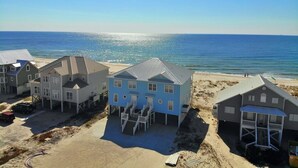 Een strandhuis met meerdere woningen, waaronder een opvallend blauw huis met balkon en overdekte veranda.