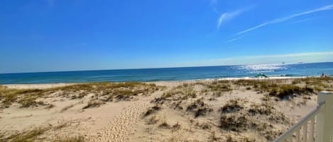 Blick auf einen Strand vom Balkon mit Geländer, feinem Sand und Meer.