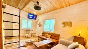 A cozy room with a wooden ceiling, a sofa, a coffee table, a TV, and a wooden wall decoration. - NEWTinycabin/Hottub/Firepit/Yard/5minParkWay (Sevier County)