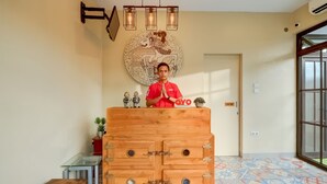 A reception desk with a wooden cabinet, a glass table, and a decorative wall piece. - Griya Gayatri Syariah (Ngaglik)