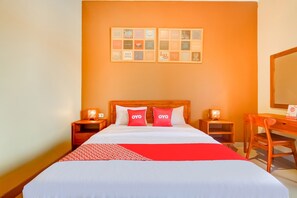 Una habitación de hotel con una cama grande, dos mesitas de noche con lámparas, un escritorio de madera y una pared decorada con cuadros.