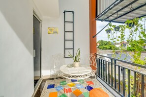 A balcony with a white metal table, a potted plant, and a colorful tiled floor. - Griya Gayatri Syariah (Ngaglik)