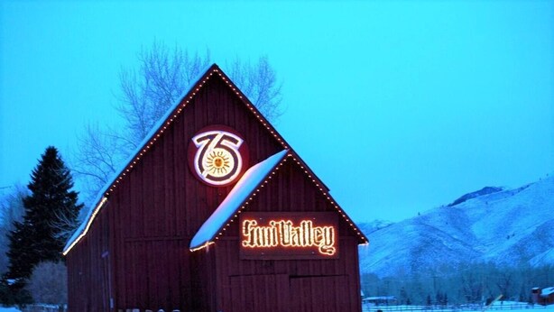 A wooden barn with a neon sign reading "76" and "Fruittalley" against a snowy landscape.