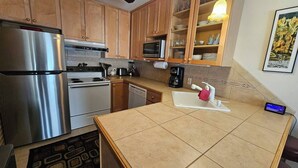 A kitchen with wooden cabinets, stainless steel appliances, a microwave, and a coffee maker.