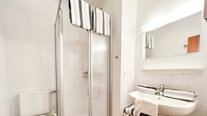 A modern bathroom with a glass-enclosed shower, a white toilet, and a sink with a mirror above. - Klaus-Groth-Str 2 App 11 Westerland (Westerland)