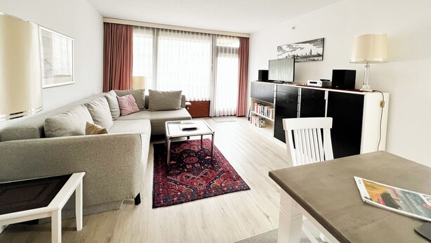 A modern living room with a sofa, a coffee table, a TV, and a bookshelf. - Klaus-Groth-Str 2 App 11 Westerland (Westerland)