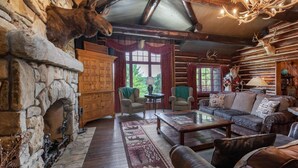 A rustic cabin interior with a stone fireplace, leather furniture, and antlers as decor. - PRIVATE 10,000 SqFt lakefront log estate  w. Pool  - Golfers Retreat - Close to Big Cedar! (kirbyville)