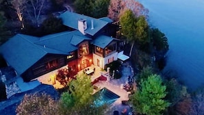 A large, multi-story house with a prominent roof and a well-lit outdoor area. - PRIVATE 10,000 SqFt lakefront log estate  w. Pool  - Golfers Retreat - Close to Big Cedar! (kirbyville)