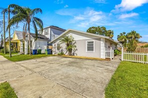 Una casa residenziale con un giardino anteriore, vialetto e una recinzione bianca a stecche.