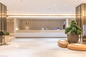 A reception area with a modern design, a reception desk, and a large potted plant. - Ji Hotel Shanghai The Bund Town City God Templ (Shanghai)
