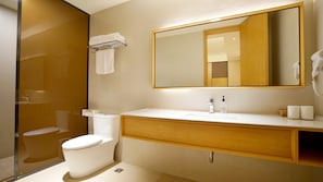 A modern bathroom with a white toilet, a sink with a mirror above it, and a glass shower enclosure. - Ji Hotel Shanghai The Bund Town City God Templ (Shanghai)
