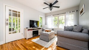 Una sala de estar con televisor, reposapiés y sofá gris.