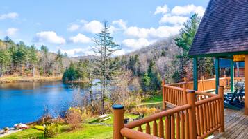 Overlooking a serene lake, this cabin features a deck with a railing and picnic area.