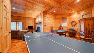 Relax by the fireplace and enjoy a game of ping pong in this inviting room with a plaid sofa.