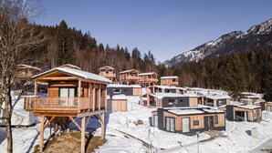 Un grupo de cabañas de madera con balcones, frente a un paisaje montañoso cubierto de nieve.