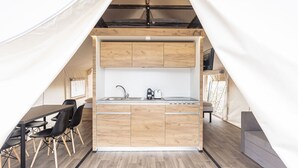 Cocina compacta con armarios de madera, un lavamanos y un comedor con sillas.