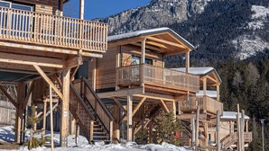 A wooden chalet with multiple balconies and a mountain backdrop.