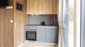 A compact kitchen with wooden cabinets, a microwave, a stove, and a sink.