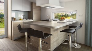 Una cucina moderna con isola centrale, sgabelli da bar e un'ampia finestra vista su spazi verdi.