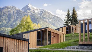 Un'accogliente baita in legno moderna con ampie finestre, con vista sulle montagne.