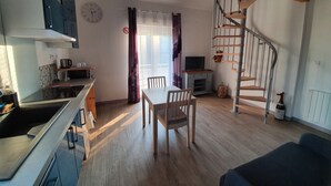 A modern kitchen with a dining area, a spiral staircase, and a living room with a sofa. - Duplex Nights & Days in Nuits-Saint-Georges (Nuits-Saint-Georges)