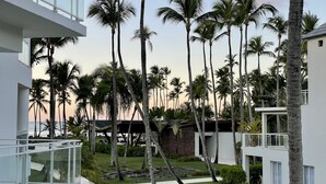 Een modern resort met een zwembad, palmbomen en uitzicht op de oceaan.