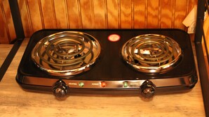 Een zwarte kookplaat met twee branders en een bedieningspaneel met knoppen voor warmte en stroom.