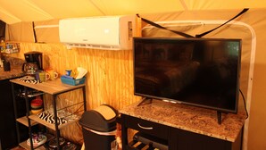 Een compacte keuken met een ingebouwde airconditioner, een flatscreen-tv en een klein eetgedeelte met een tafel in zebraprint.
