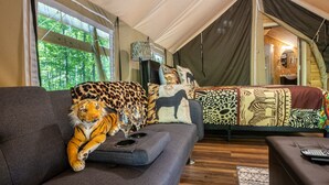 Een tentaccomodatie met een bank en een bed, beide met gekleurde kussens.