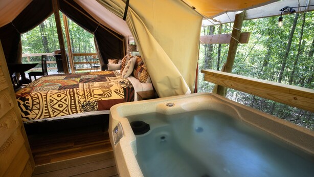 Een tentaccommodatie met een hottub en een bed met beddengoed met een patroon.