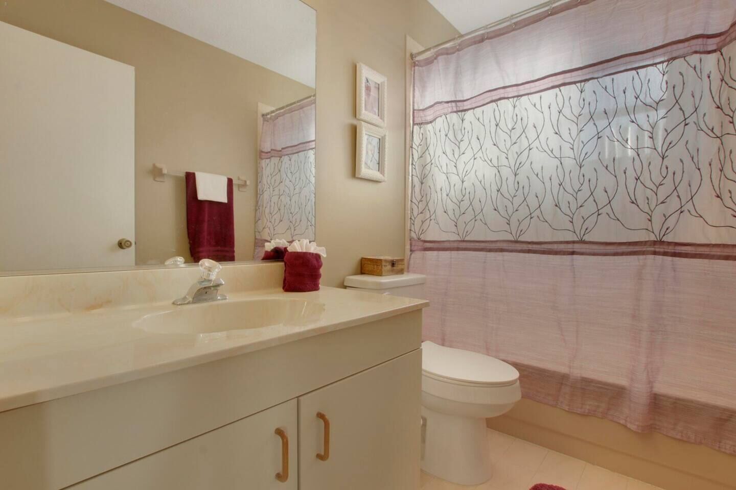 A bathroom with a sink, mirror, toilet, and shower curtain.