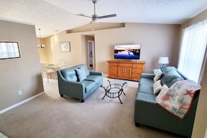 Ein Wohnzimmer mit zwei Sofas, einem Couchtisch, einem Fernseher und einem Deckenventilator.