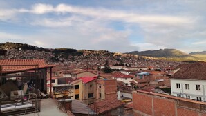 A residential area with terracotta-tiled rooftops, a mix of single and multi-story buildings, and a hilly backdrop. - Friendly and comfortable apartment in Cusco (cusco)