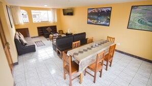 A living room with a sofa, a dining table with chairs, a fireplace, and a TV mounted on the wall. - Friendly and comfortable apartment in Cusco (cusco)