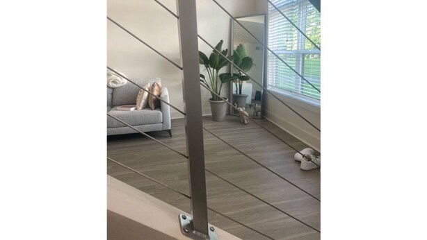 A modern interior with a grey sofa, a potted plant, and a large window with blinds. - Modern loft near Braves Stadium (Cabo San Lucas)
