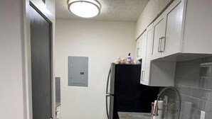 A narrow kitchen with white cabinets, a black refrigerator, and a granite countertop. - Modern loft near Braves Stadium (Cabo San Lucas)