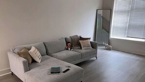 A grey sectional sofa with two pillows, a tablet, and a remote control on it. - Modern loft near Braves Stadium (Cabo San Lucas)