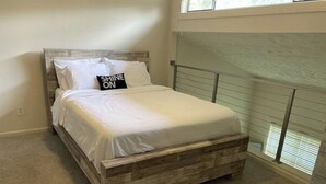A bedroom with a wooden bed frame, white bedding, and a pillow with "SHINE ON" text. - Modern loft near Braves Stadium (Cabo San Lucas)