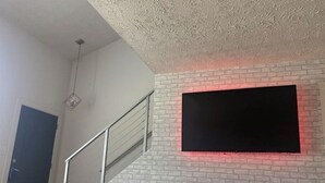 A staircase with a white brick wall and a flat-screen TV mounted on it. - Modern loft near Braves Stadium (Cabo San Lucas)