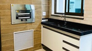 A kitchen with a built-in oven, a window above the sink, and a ventilation system on the wall. - Arraial Praia dos Anjos Residence Club (Arraial do Cabo)