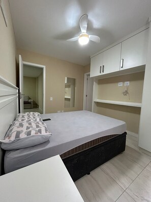 A bedroom with a bed, a ceiling fan, and built-in cabinets. - Arraial Praia dos Anjos Residence Club (Arraial do Cabo)