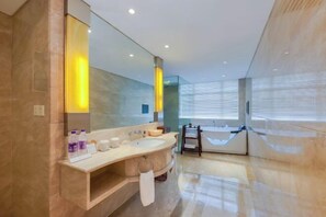 A modern bathroom with a large mirror, two sinks, a bathtub, and a vanity with toiletries. - Zhengzhou GDH Hotel (Zhengzhou)