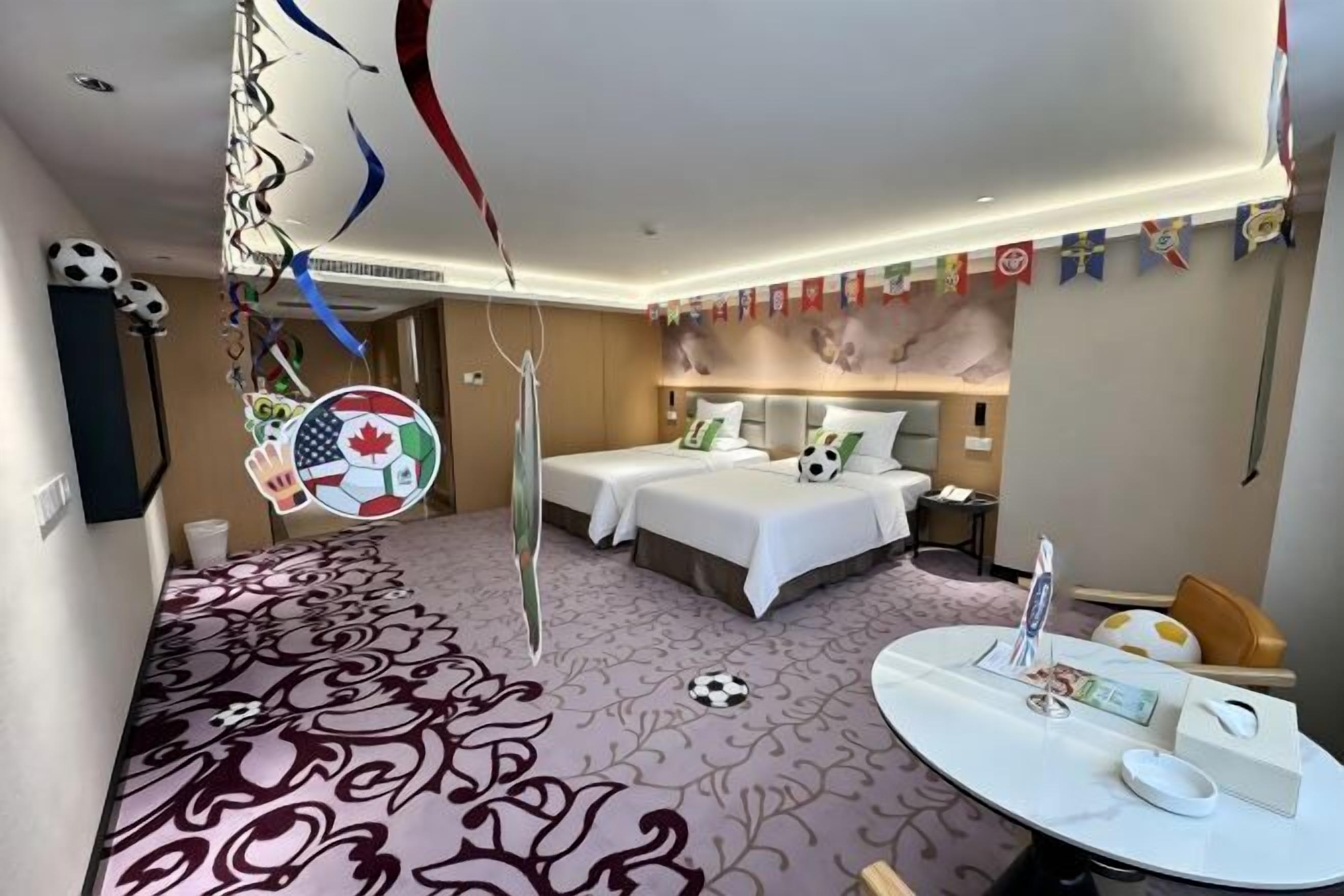 A hotel room with a bed, bedside tables, a desk, and a large window.