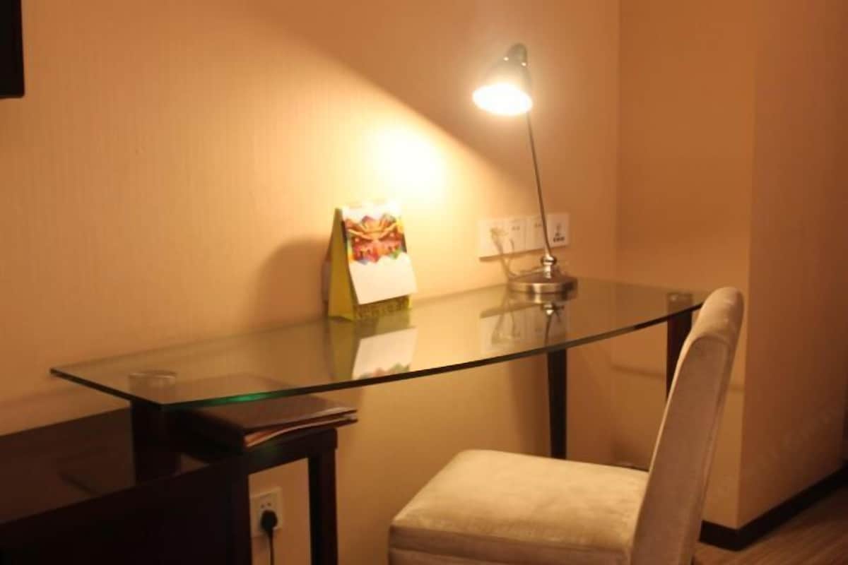 A small, well-lit room with a glass-top table, a chair, and a lamp.
