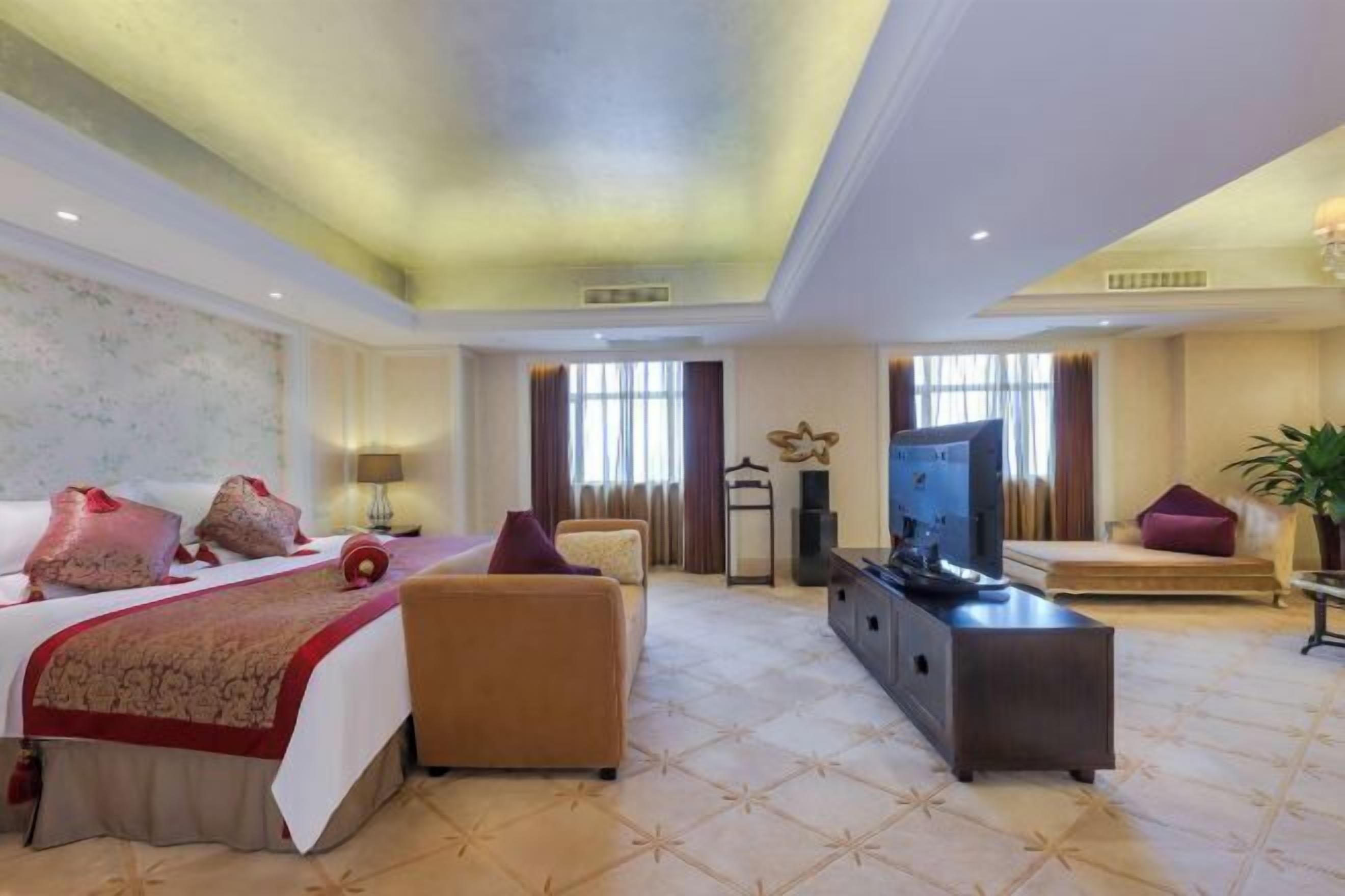 A hotel room with a bed, a sofa, a TV, and a console table.