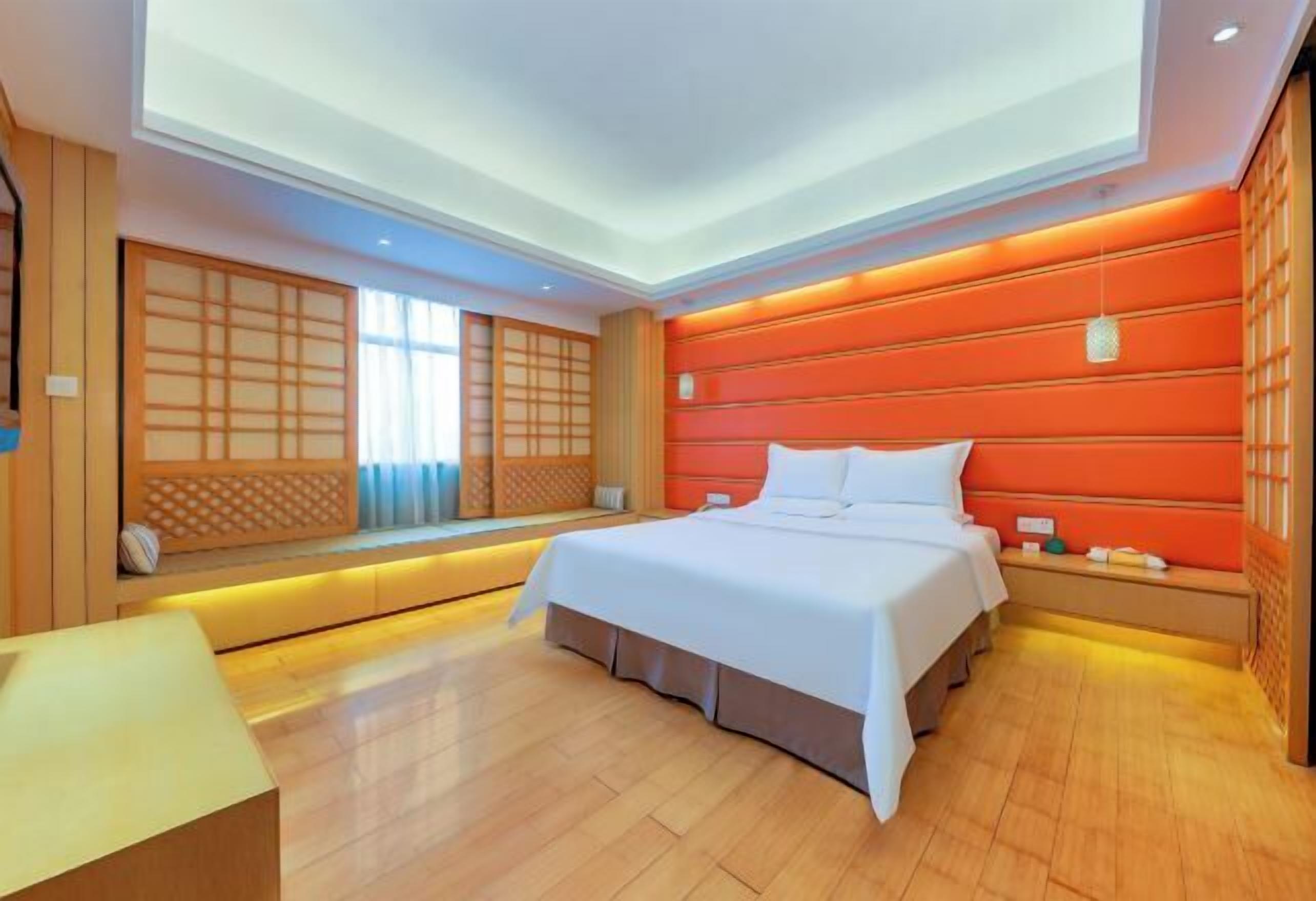 A modern hotel room with a large bed, built-in seating, and a wooden floor.